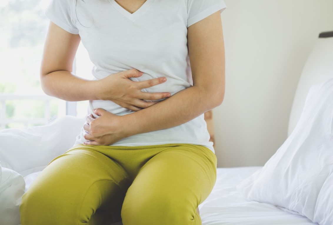 Woman with gut issues grasping her stomach in discomfort