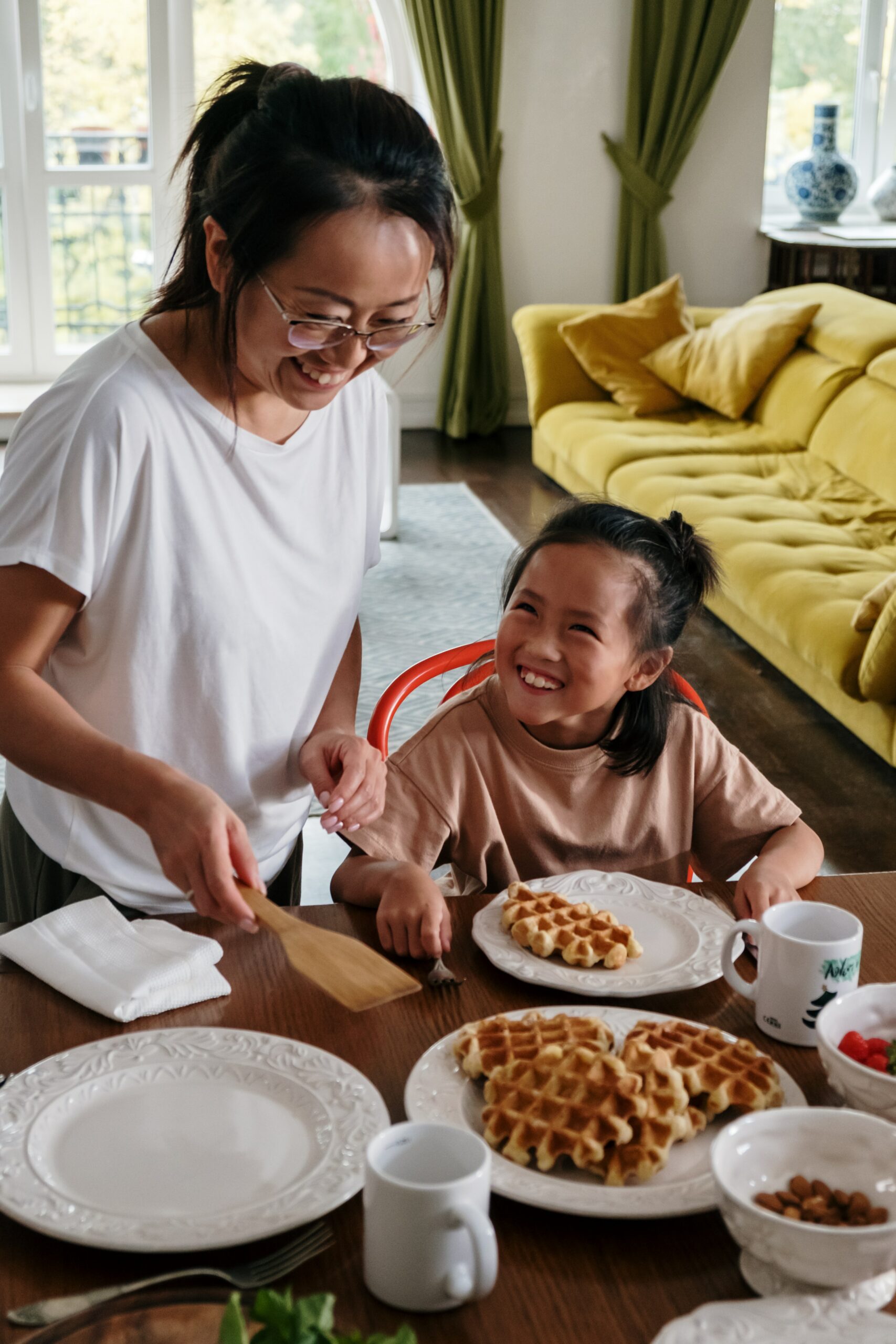 Woman giving her daughter waffles for breakfast